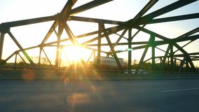 Time lapse view of traffic crossing iron truss bridge during golden hour sunset with dramatic sunburst and lens flare effects creating cinematic atmosphere. - Powered by Shutterstock - Get 15% off with code: PIKWIZARD15