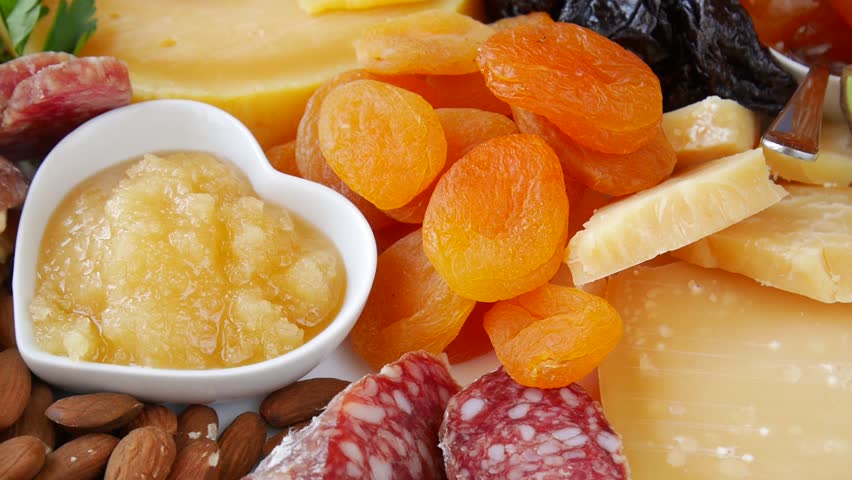Delicious assorted appetizer with cheese, dried fruit, salami, nuts and jam rotating.