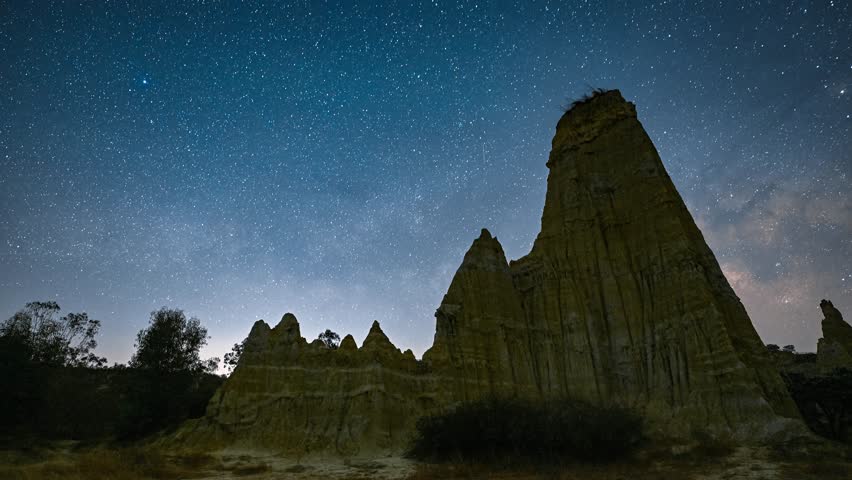 Spectacular Milky Way galaxy stretching across starry night sky above dramatic rock formations in Yunnan Province, China, creating stunning astrophotography landscape.