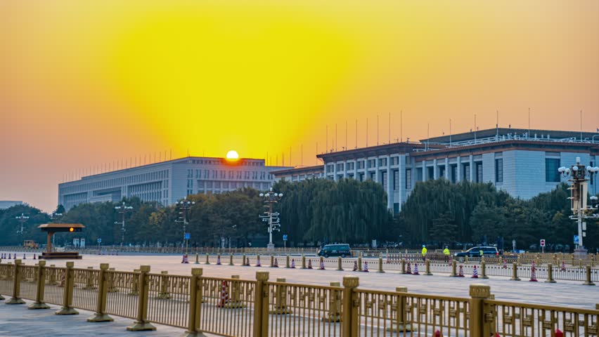 Beautiful sunrise time lapse over the Great Hall of the People in Beijing, China with golden sky and government buildings in the background
