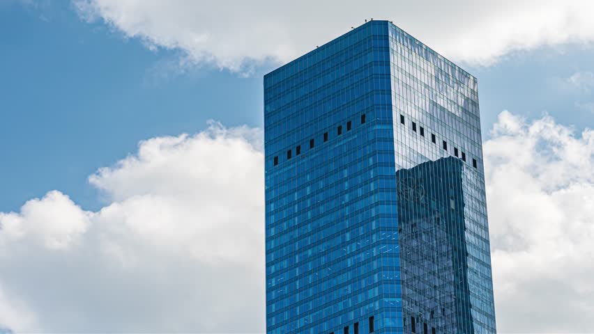 Modern blue glass office building towering against cloudy sky, perfect for business and corporate video content showcasing urban architecture and professional environments. - Powered by Shutterstock - Get 15% off with code: PIKWIZARD15