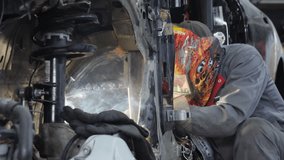 Worker in protective mask welds carcass of damaged car in repair shop. Mechanic fixes vehicle body with welding machine at service station - Powered by Shutterstock - Get 15% off with code: PIKWIZARD15