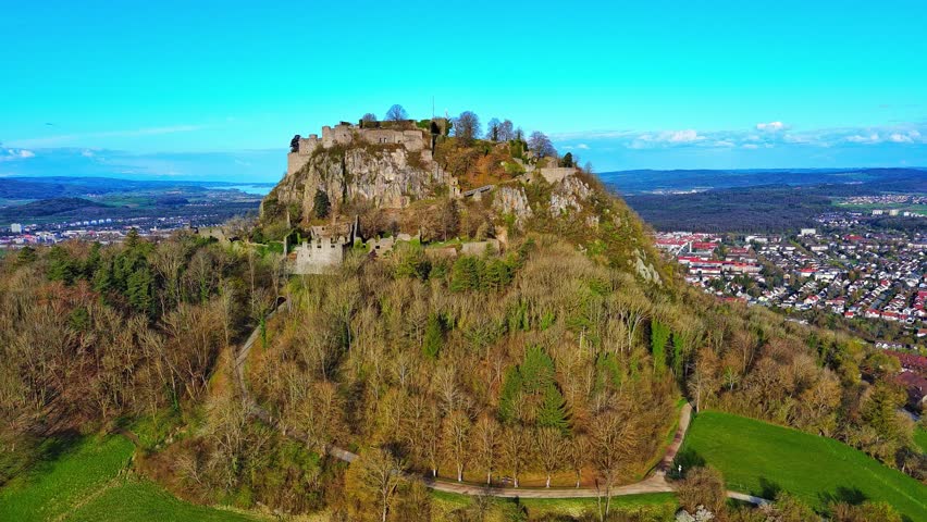 Aerial view of a hill with the ruins of the Hohentwil castle on its top against a blue sky