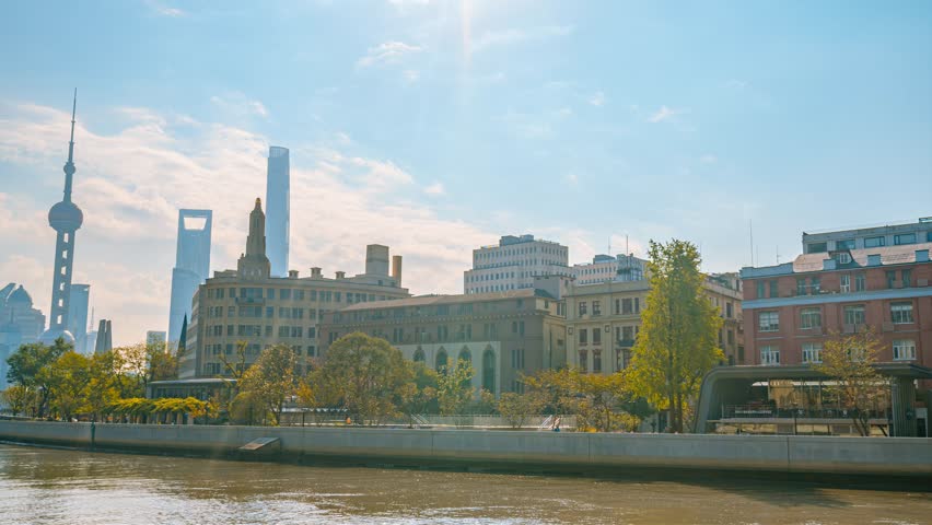 Shanghai Bund waterfront skyline with Oriental Pearl Tower and historic colonial architecture viewed from Huangpu River during golden hour backlighting