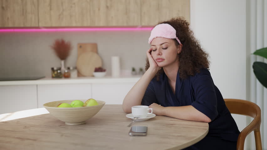 Exhausted young woman drinking morning coffee, suffering from sleep issues