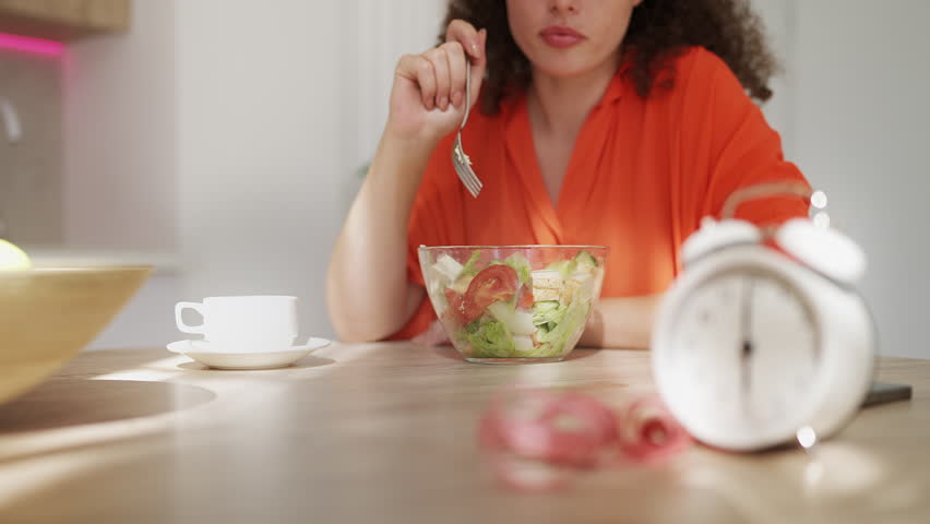 Woman eating fresh salad, practicing intermittent fasting with healthy nutrition