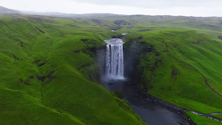 Skogafoss waterfall flowing through green cliffs in Iceland.  4k aerial slow motion view of epic waterfall, Skogafoss waterfall - one of the most popular waterfalls in Iceland.
