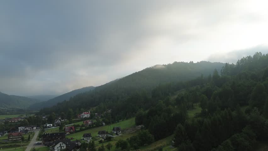 Aerial panorama of green hills under fog and clouds