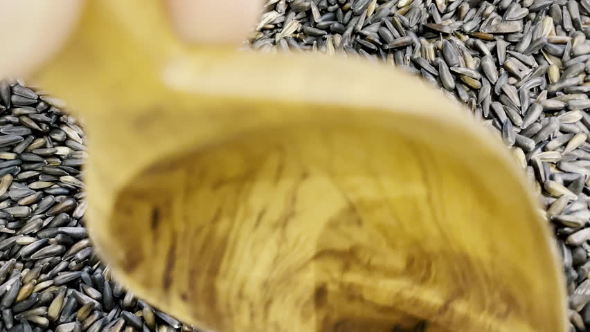Close-up view of a wooden scoop picking Nyjer Seeds