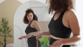 Curly-haired woman measuring waist, upset with excess weight and insecurities - Powered by Shutterstock - Get 15% off with code: PIKWIZARD15