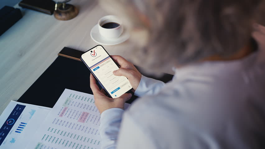Grey-haired businesswoman voting online on mobile phone for her candidate