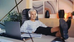 Restful senior woman in headset listening to music, pleased with finished work - Powered by Shutterstock - Get 15% off with code: PIKWIZARD15