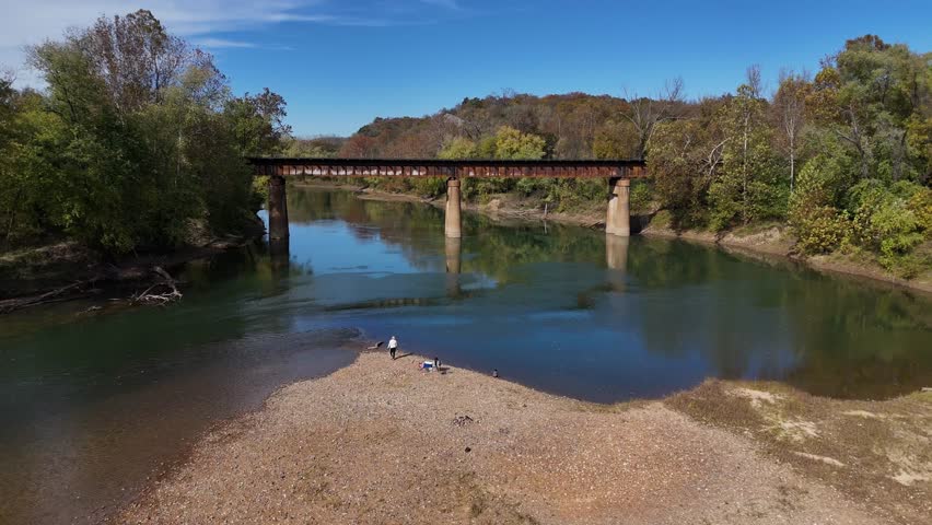 Aerial view of the Rail Bridge over the Meramec River, with autumn trees lining the banks and people on a sandbar, Ballwin, Missouri, United States.