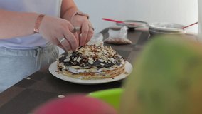 Close up of woman’s hands topping a crepe cake with chocolate ganache, sliced almonds, and chopped nuts - Powered by Shutterstock - Get 15% off with code: PIKWIZARD15