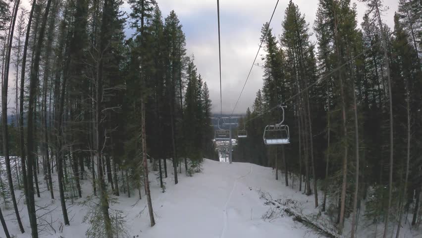 Aerial view of a scenic ski trail winding through a snowy mountain landscape in Banff National Park, Canada. The winter scene captures crisp white slopes surrounded by dense pine forest in cloudy day	