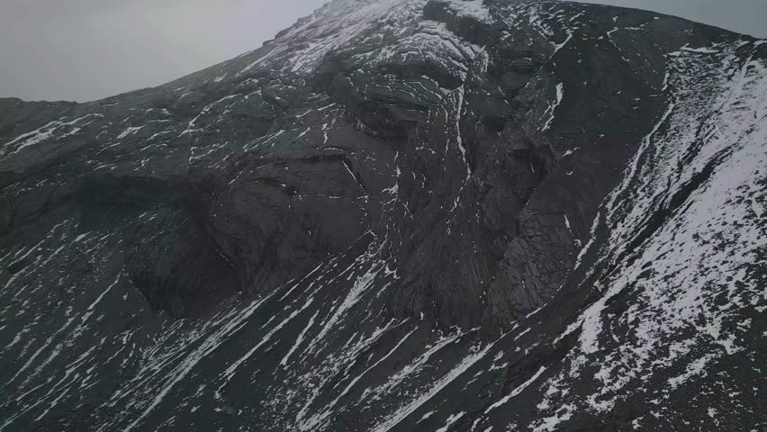 Aerial view of a scenic ski trail winding through a snowy mountain landscape in Banff National Park, Canada. The winter scene captures crisp white slopes surrounded by dense pine forest in cloudy day	