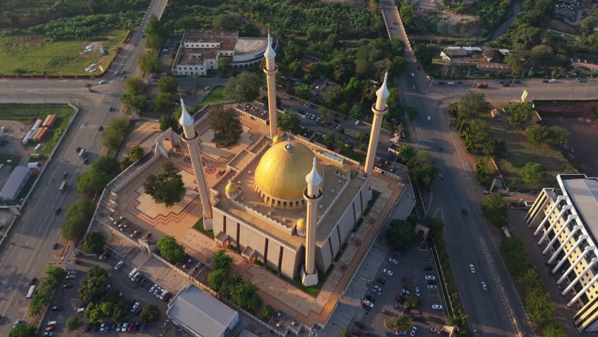 Aerial view of the National Mosque with its golden dome and towering minarets, surrounded by lush greenery and roads, Abuja, Federal Capital Territory, Nigeria.