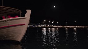 A boat is in the water with a full moon in the background. The moon is reflecting on the water, creating a serene and peaceful atmosphere - Powered by Shutterstock - Get 15% off with code: PIKWIZARD15