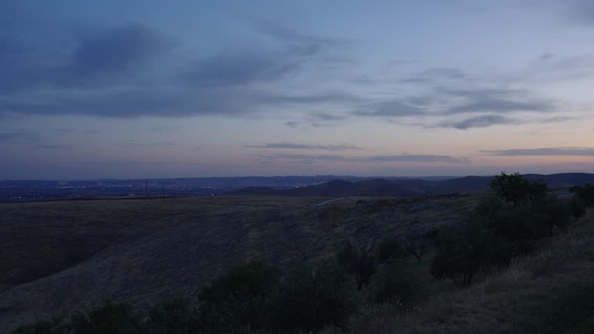Distant view of Sanliurfa Haliliye city at dusk with lights turning on, filmed from Göbeklitepe