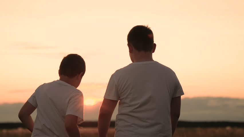 Child kid boys dancing sunset, children jumping up down, people outdoors having fun together, white t-shirts and a painted sky, backlit kids enjoying an evening sky, kids dancing in warm sunset glow