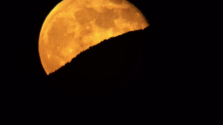 Super moon rising from behind a mountain ridge