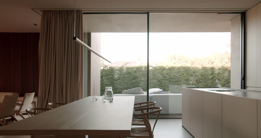 Modern dining room with glass sliding doors opens to patio, wooden table, and minimal interior design. peaceful ambiance. contemporary living and interior design