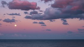 Time lapse: Full moon rising above calm sea under violet pink twilight sky with scattered clouds creating serene atmosphere of peace balance and wonder symbolizing harmony between nature and cosmos - Powered by Shutterstock - Get 15% off with code: PIKWIZARD15