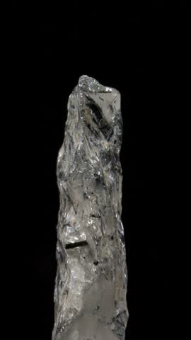 Rutilated Quartz (quartz containing needle-like inclusions of rutile) sample rotating against a black background. Vertical