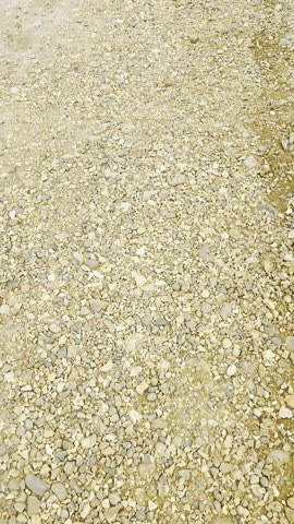 Point-of-view video of a person walking on a dirt and gravel path, showing natural ground texture, pebbles, and casual outdoor movement