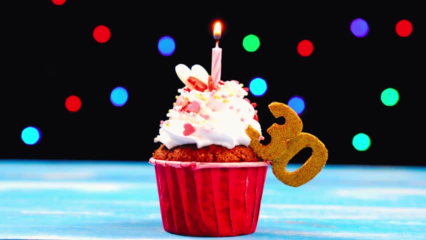 Delicious birthday cupcake with a burning candle and number 30 topper, glowing warmly against a multicolored lights background — celebrating a cheerful 30th birthday milestone. - Powered by Shutterstock - Get 15% off with code: PIKWIZARD15