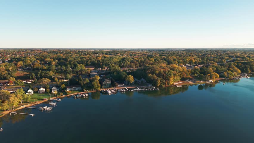Drone aerial of freshwater bodies of water at Twin Lakes, Wisconsin summer vacation landscape during sunny  and warm early morning day above blue fresh water, homes, boat docks, and forest tree woods