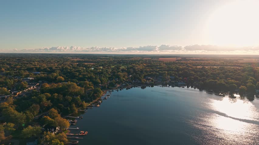 Drone aerial of freshwater bodies of water at Twin Lakes, Wisconsin summer vacation landscape during sunny  and warm early morning day above blue fresh water, homes, boat docks, and forest tree woods