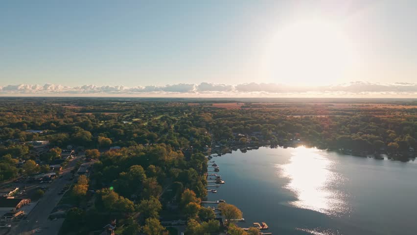 Drone aerial of freshwater bodies of water at Twin Lakes, Wisconsin summer vacation landscape during sunny  and warm early morning day above blue fresh water, homes, boat docks, and forest tree woods