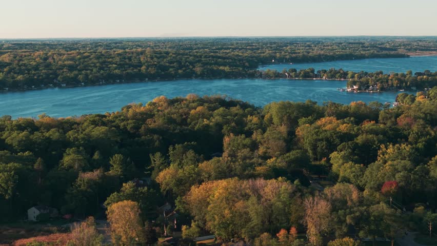 Drone aerial of freshwater bodies of water at Twin Lakes, Wisconsin summer vacation landscape during sunny  and warm early morning day above blue fresh water, homes, boat docks, and forest tree woods