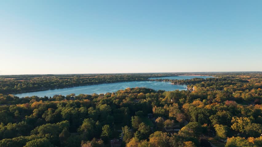 Drone aerial of freshwater bodies of water at Twin Lakes, Wisconsin summer vacation landscape during sunny  and warm early morning day above blue fresh water, homes, boat docks, and forest tree woods