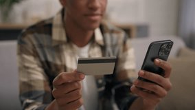 Ethnic African American man buyer shopping with credit card and mobile phone male guy at home using smartphone bank application buying goods online e-commerce paying with telephone internet ordering - Powered by Shutterstock - Get 15% off with code: PIKWIZARD15