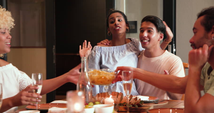 Happy diverse couple and friends talking, eating snacks and drinking champagne at dinner party. celebration, dinner party, lifestyle and friendship concept.
