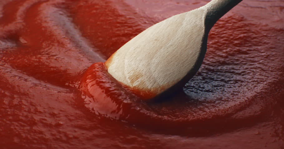 Slow motion close-up of thick rich red tomato sauce being stirred with a wooden spoon at 1000 fps.Concept Italian tradition and the art of simple cooking. 
