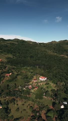 A beautiful mountain view with a house in the middle. The house is surrounded by trees and the sky is clear