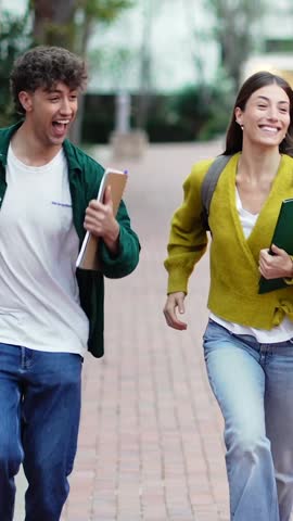 Two happy University students running on campus going to classes, celebrating exams