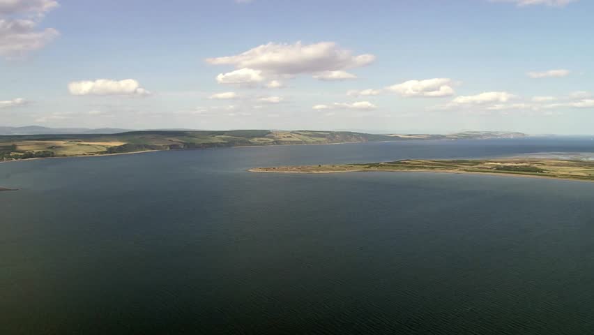 Beautiful coastal landscape with blue water and green hills under a cloudy sky