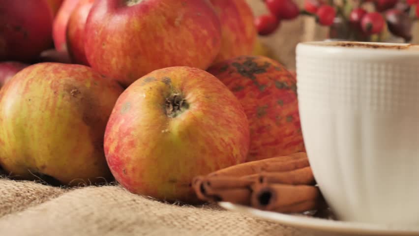 cinnamon and red apples - Several whole, aromatic cinnamon sticks stacked on a white plate on a rustic burlap background