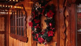 christmas wreath with red poinsettia flowers and golden bows hanging on rustic wooden stall wall at festive holiday market, concept of christmas decorations, winter fair, seasonal celebration - Powered by Shutterstock - Get 15% off with code: PIKWIZARD15