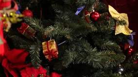 Close-up of a Christmas tree adorned with red balls, gold bows, purple ribbons and tiny wrapped presents in a colorful holiday setting - Powered by Shutterstock - Get 15% off with code: PIKWIZARD15