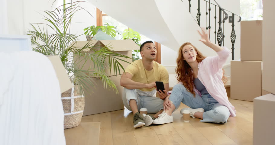 Happy man and his partner moving into new home., sitting on floor using phone with boxes new home, home ownership, mortgage. new beginnings., family life, happiness, lifestyle and relationship
