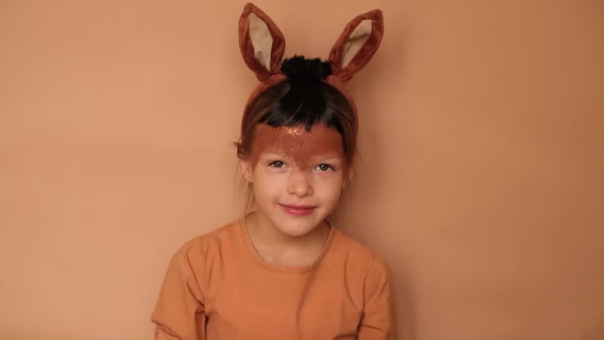  A shy child dressed up as a horse with a painted face and ears on his head hides behind paper numbers 2026.