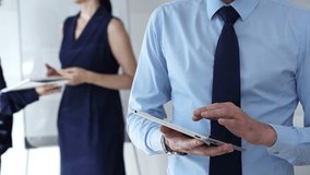 Businessman hands holding and using a digital tablet for work, navigating information and checking data during a modern corporate meeting - Powered by Shutterstock - Get 15% off with code: PIKWIZARD15