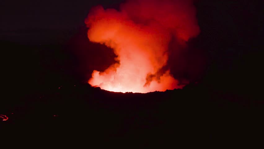 Volcanic eruption at night with glowing lava and smoke plumes