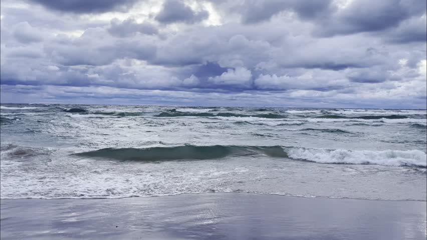 Stormy Lake Michigan shoreline in Oceana County, dark thunderclouds over rough freshwater waves and reflective wet sand at dusk