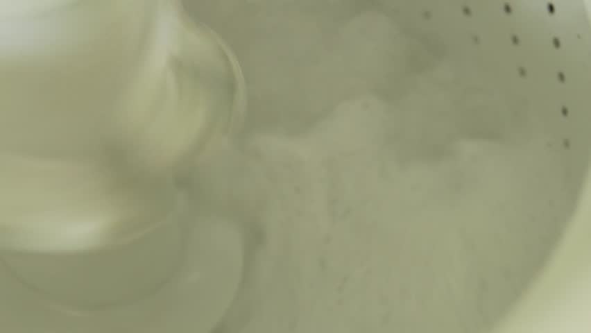 Water and soap suds swishing around clothes in an operating washing machine during its wash cycle